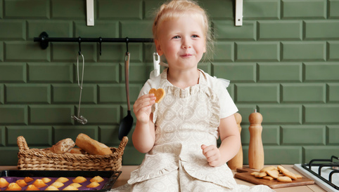 Alete bewusst Mädchen sitzt auf der Küchenzeile und isst selbstgebackene Kekse