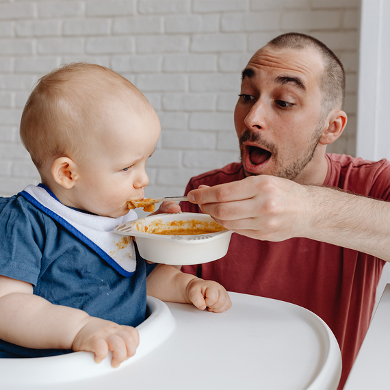 Papa füttert Baby mit Brei